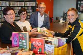 Susanne Stengel, Anett Schäfer von der Stadtbibliothek Flöha und Oberbürgermeister Volker Holuscha nehmen die Bücherspende von Politikbeauftragten der DHL Group Vincent Ackermann entgegen. Foto: Stadtverwaltung Flöha/ Erik Frank Hoffmann